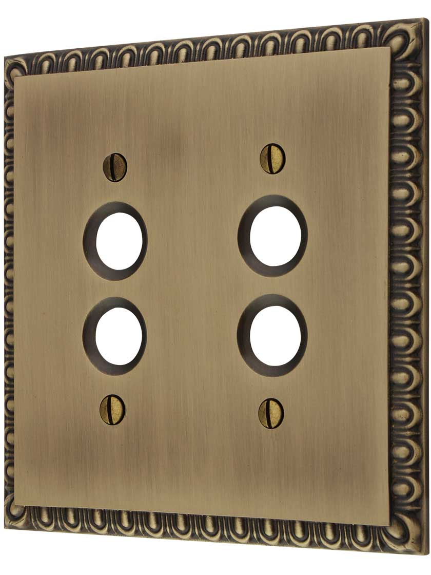 Ovolo Double Gang Push-Button Switch Plate in Antique Brass.